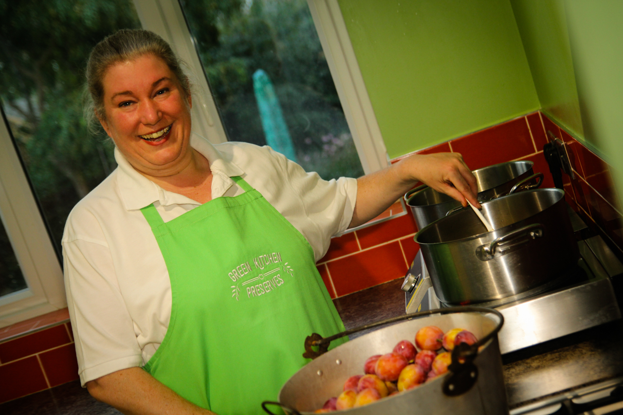 a photo of alison cox in the green kitchen preserves kitchen stirring chutney in a pot