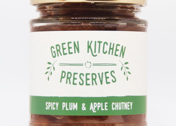 a jar of spicy plum & apple chutney on a white background