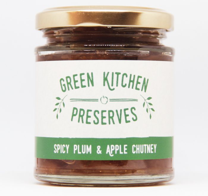 a jar of spicy plum & apple chutney on a white background